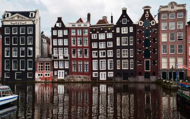 Kanalhuse i Amsterdam, der spejler sig i vandet